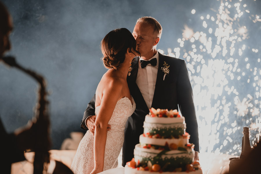 Bacio degli Sposi con la Torta Nuziale ed i Fuochi D'Artificio durante il Matrimonio alla Torre di Scopello