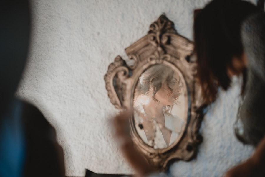 Foto in primo piano della sposa attraverso uno specchio antico all'interno della Torre di Scopello