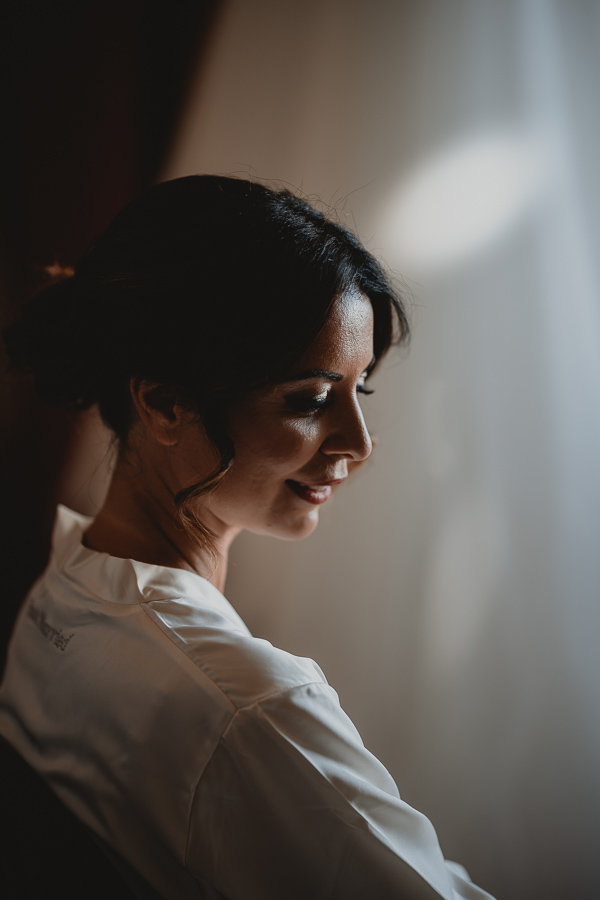 Foto in primo piano della sposa in vestaglia mentre si prepara prima del matrimonio