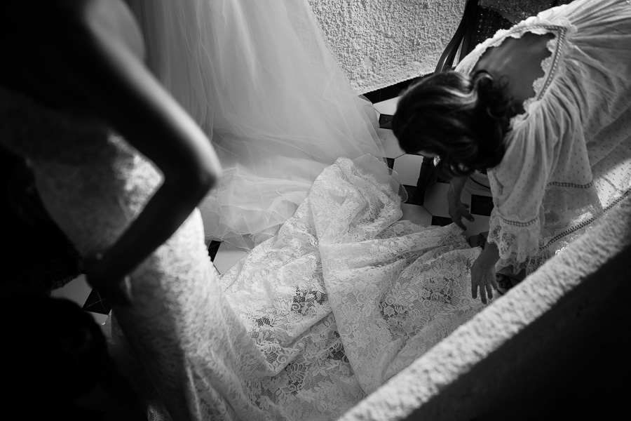 Foto spontanea della sposa con un'invitata mentre l'aiuta a sistemare l'abito nuziale