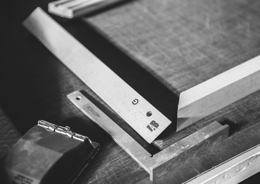 Black-and-white photograph of measuring tools and a wooden frame in the Lab Service workshop.